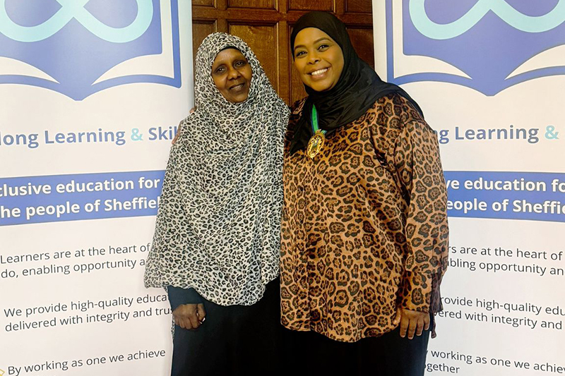 Two women stood in front of Lifelong Learning and Skills banners